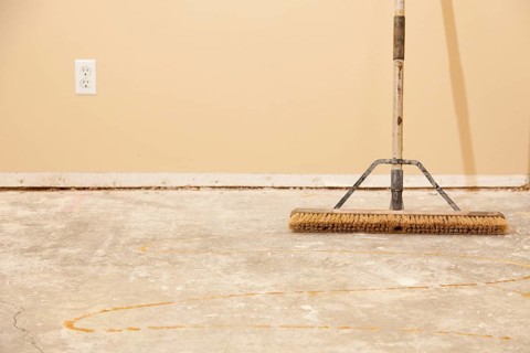 Blank concrete house floor with broom ready for flooring installation