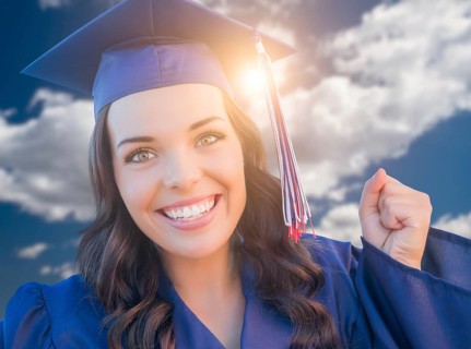 Happy graduating mixed-race woman in cap and gown