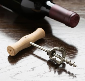 Abstract wine bottle and corkscrew laying on a reflective wood surface