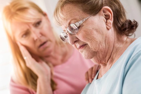Young adult woman consoles sad senior adult female