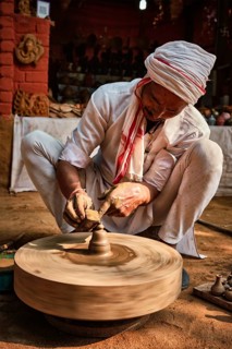 Indian potter at work: throwing the potter's wheel and shaping ceramic vessel and clay ware: pot