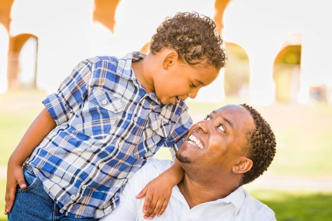 Happy african american father and mixed-race son playing at the park