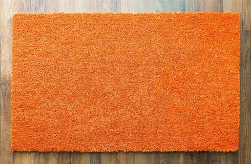 Blank orange welcome mat on wood floor background ready for your own text