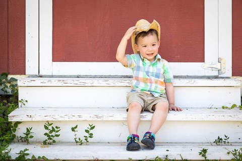 Young mixed-race chinese and caucasian boy wearing cowboy hat relaxing on the steps
