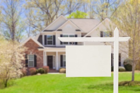 Blank real estate sign in front of beautiful new house