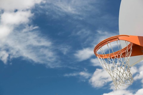 Abstract of community basketball hoop and net against blue sky