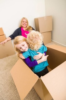 Playful young family in empty room playing with moving boxes