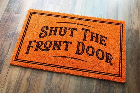 Shut the front door halloween orange welcome mat on wood floor background