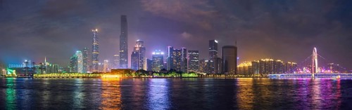 Guangzhou cityscape skyline over the Pearl River with Liede Bridge illuminated in the evening. Guangzhou