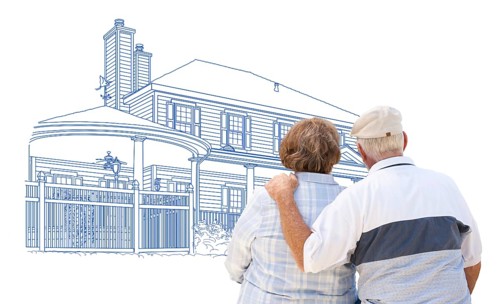 Curious embracing senior couple looking at house drawing on white