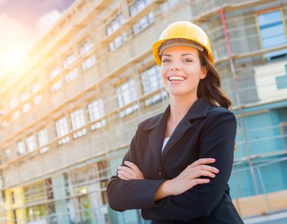 Portrait of young attractive professional female contractor wearing hard hat at construction site