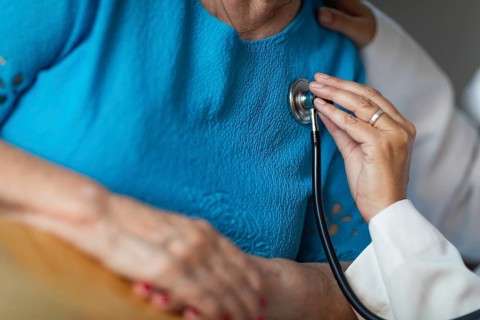 Female doctor checking the heart with stethoscope of senior adult woman