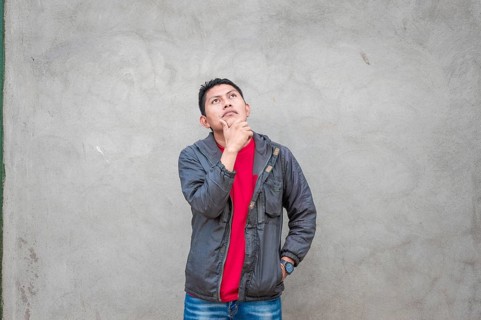 Young man wondering with his hand on his chin on an isolated background