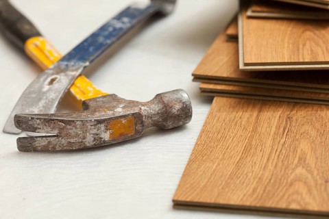 Worn hammer and pry bar with laminate flooring abstract