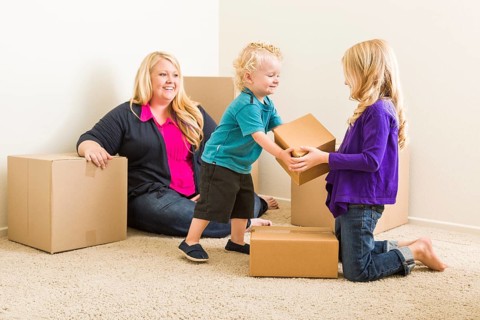 Happy young family in empty room with moving boxes