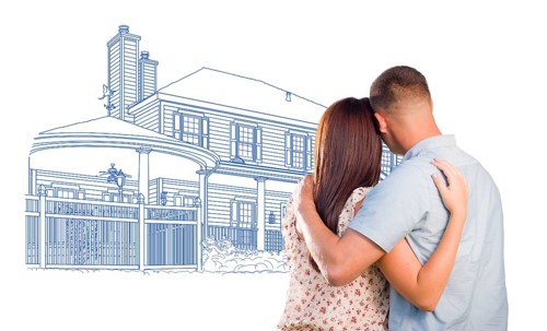 Embracing military couple looking at house drawing on white