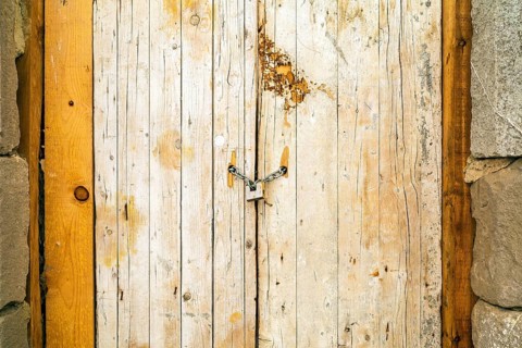 Rusty padlock locking old wooden door with a chain