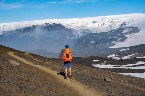 Hikers on trail through volcanic landscape