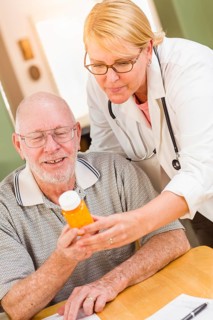 Doctor or nurse explaining prescription medicine to attentive senior man