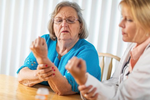 Female doctor talking with senior adult woman about hand therapy