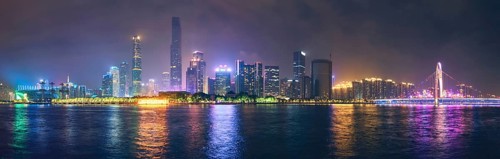 Guangzhou cityscape skyline over the Pearl River with Liede Bridge illuminated in the evening. Guangzhou
