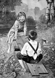 Children playing with a seesaw on the meadow and having fun