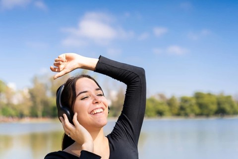 Young woman listening to music outdoors with headphones. Expression of happiness