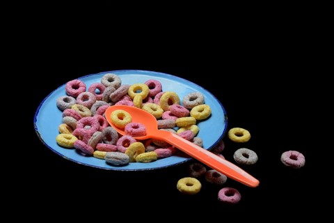 Fruit-flavoured cereal rings in plate with spoon