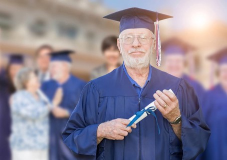 Proud senior man in hat and gown at outdoor graduation ceremony