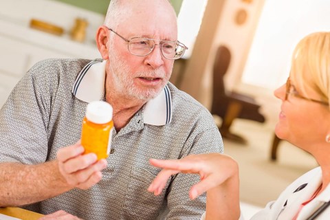 Doctor or nurse explaining prescription medicine to attentive senior man