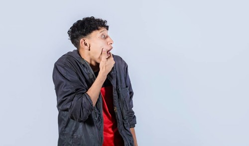 Amazed young man with hand near open mouth