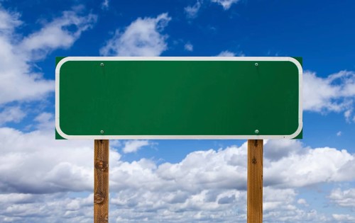 Blank green road sign with wooden posts over blue sky and clouds