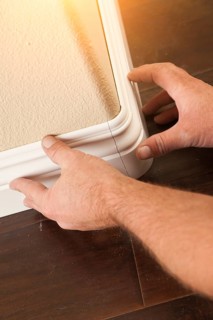 Contractor installing new baseboard with bull nose corners and new laminate flooring renovation abstract