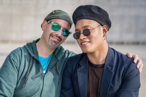 Gay Latino male couple sitting on a bench in a park