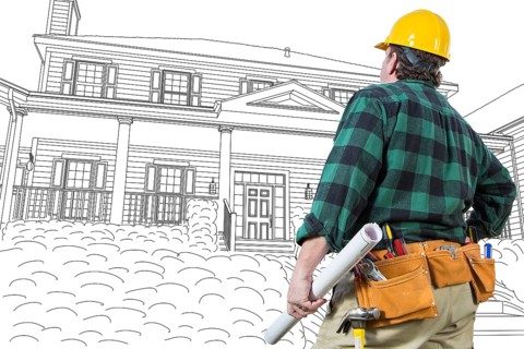 Male contractor with hard hat and tool belt looking at custom house drawing on white