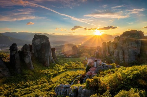 Sunset over monastery of Rousanou and Monastery of St. Nicholas Anapavsa in famous greek tourist destination Meteora in Greece on sunset with sun rays and lens flare