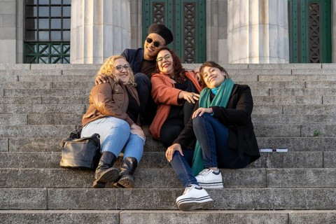 Multi ethnic group of friends sitting on some stairs having a good time chatting and laughing