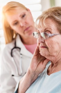 Melancholy senior adult woman being consoled by female doctor or nurse