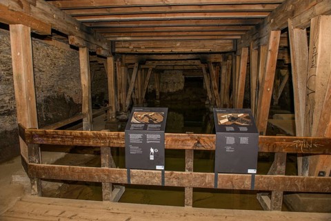 Tourist information board on the construction of an amphitheatre in the basement of the arena cellar of the historic Roman amphitheatre of Trier Treverorum Augusta with wooden supports in groundwater