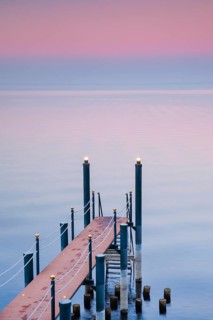 Rosa Abendstimmung ueber dem Bodensee mit beleuchtetem Badesteg zum See