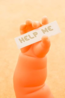 Toy doll hand holding paper with HELP ME wording