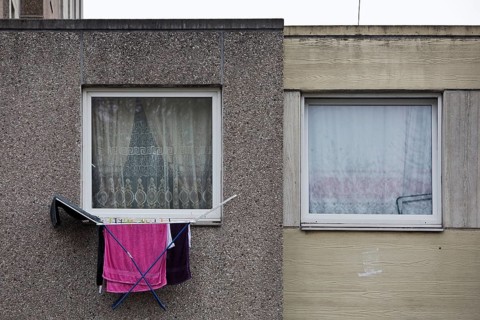 Laundry rack hanging out of the window on the first floor of a dreary apartment block