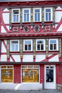 Historic half-timbered house with colourfully painted and carved wooden beams and family coat of arms