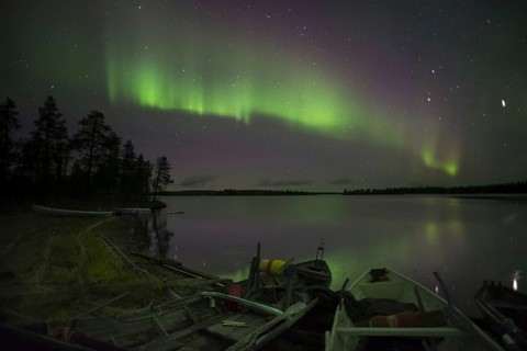 Aurora and stars over the lake with stranded canoes at night