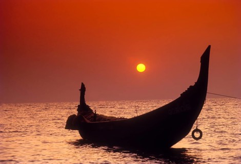 The Setting sun framed by the crescent shaped stern of a Catamaran in Kozhikode