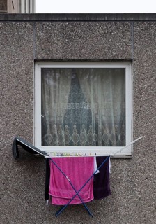 Laundry rack hanging out of the window on the first floor of a dreary apartment block