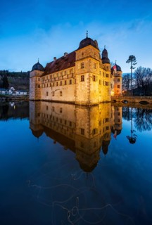 The illuminated moated castle Mitwitz in the evening