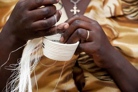 Close-up of a lady weaving a traditional basket at the Ladies' Cooperative