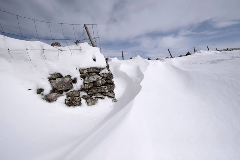 Wind-blown snowdrift on the back of a dry stone wall after a heavy snowstorm