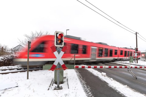 Passing train at a level crossing with barriers in sleet